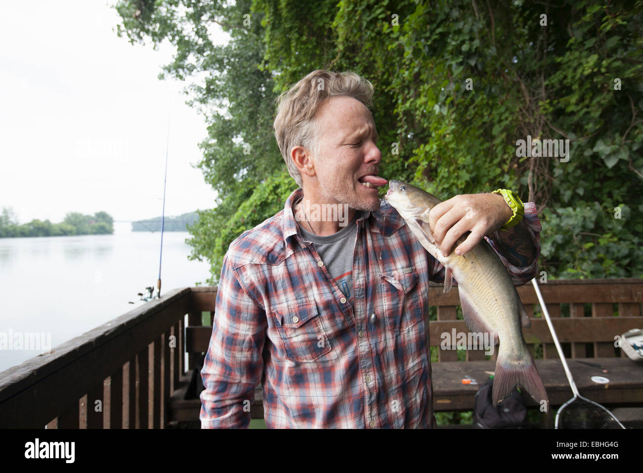 Man sticking out tongue at catfish, river Raisin, Monroe, Michigan, USA Stock Photo