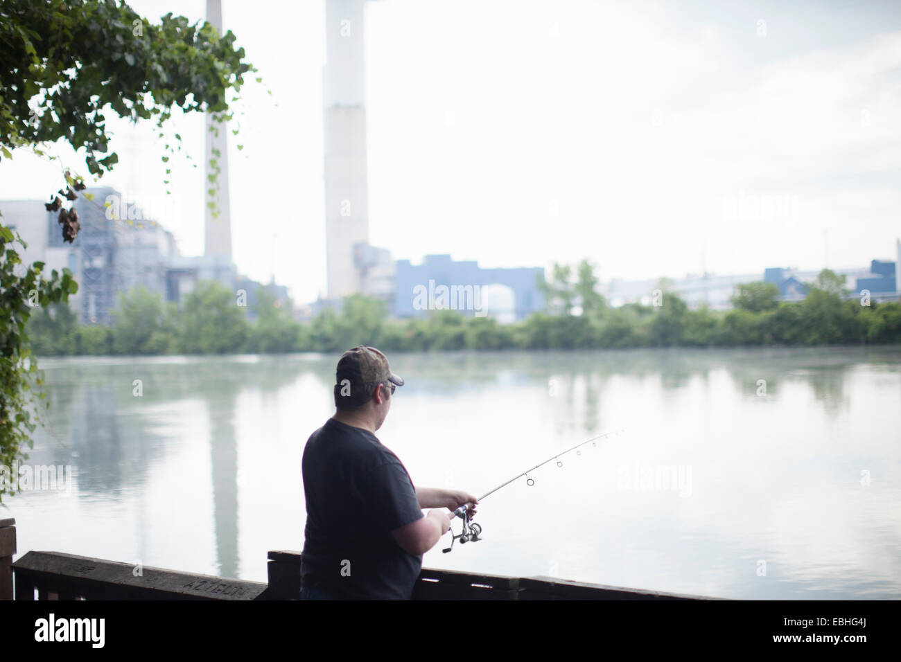 Man fishing opposite Detroit Edison Power Station, river Raisin, Monroe, Michigan, USA Stock Photo