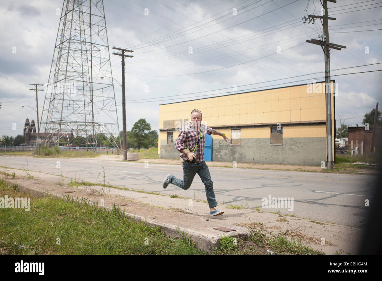 Man running in panic along industrial road, Detroit, Michigan, USA Stock Photo