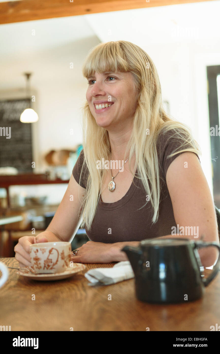 Mid adult woman drinking tea in country store cafe Stock Photo
