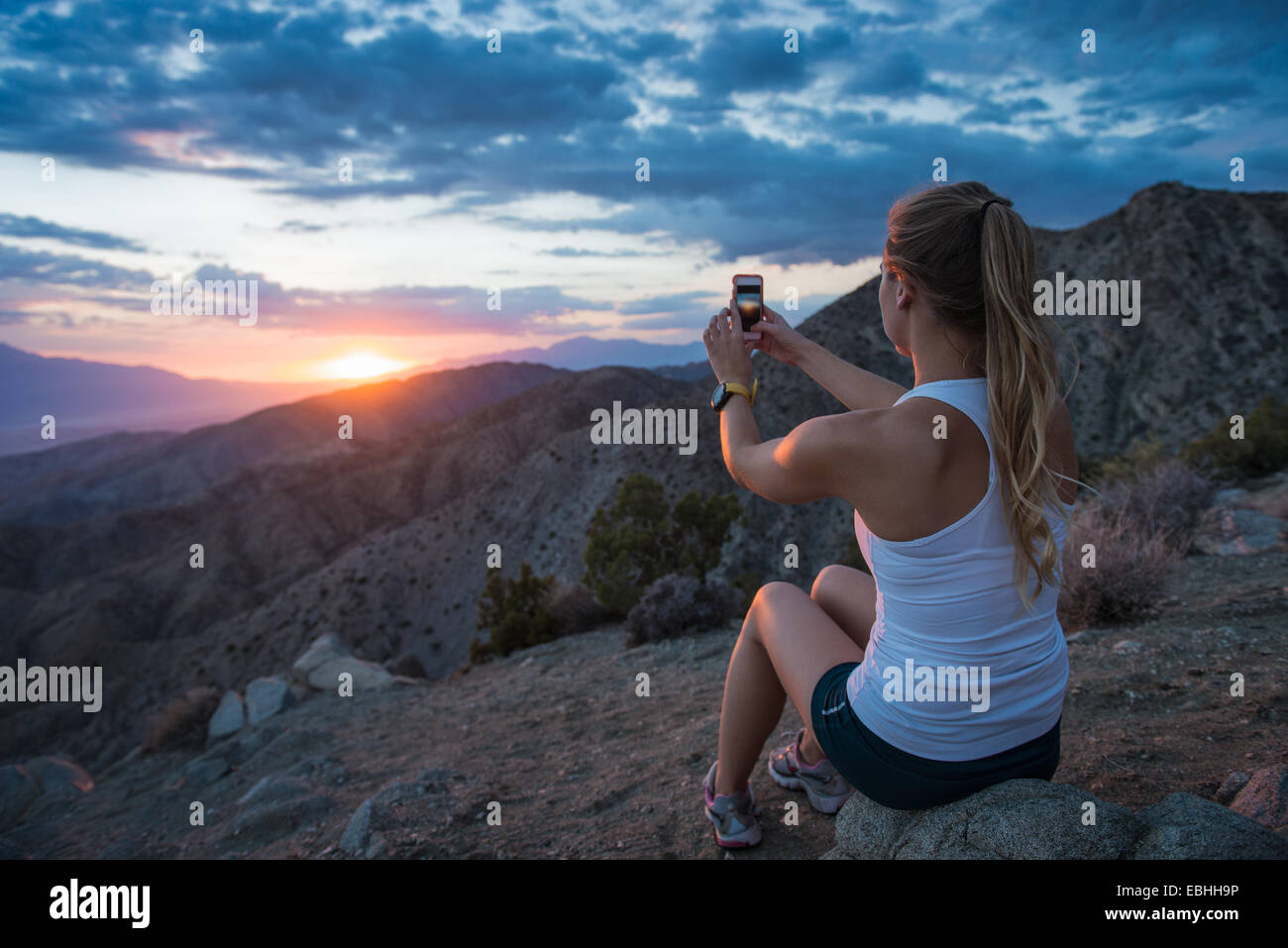Woman taking photo of mountain, Joshua Tree National Park, California, US Stock Photo