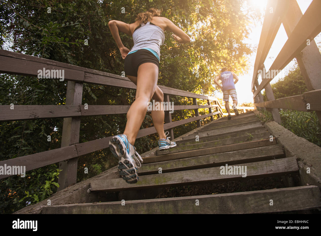 Mid adult man and young woman running up steps, rear, low angle view Stock Photo