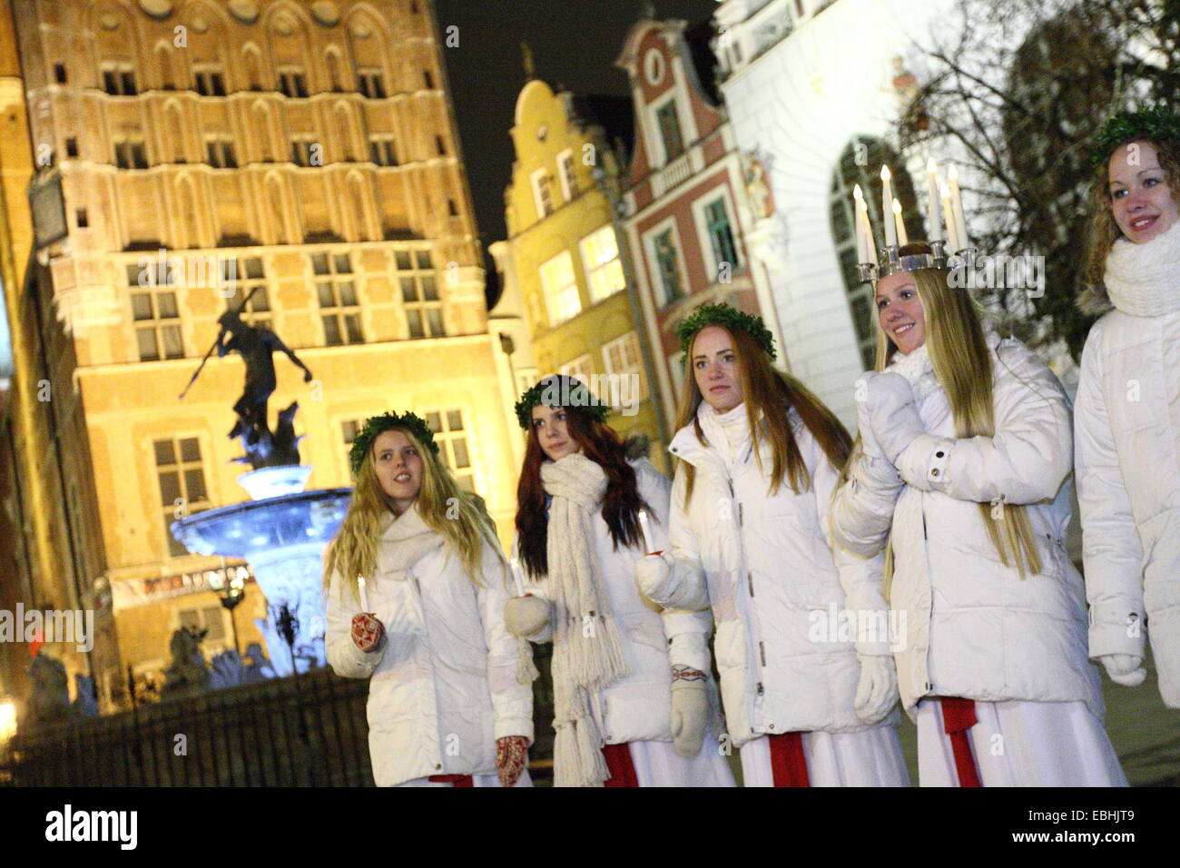 Gdansk, Poland 1st, Dec. 2014 Young girls from Kalmar, Sweden dressed in a white dress and a red sash (as the symbol of martyrdom) carries candles in proccesion along the Gdansk Old City centre. One of them (Stina Mattisson) wears a crown of candles on her head. Girls dressed as Lucy carry cookies in procession and sing a songs. It is said that to vividly celebrate St. Lucy's Day will help one live the long winter days with enough light. Credit:  Michal Fludra/Alamy Live News Stock Photo
