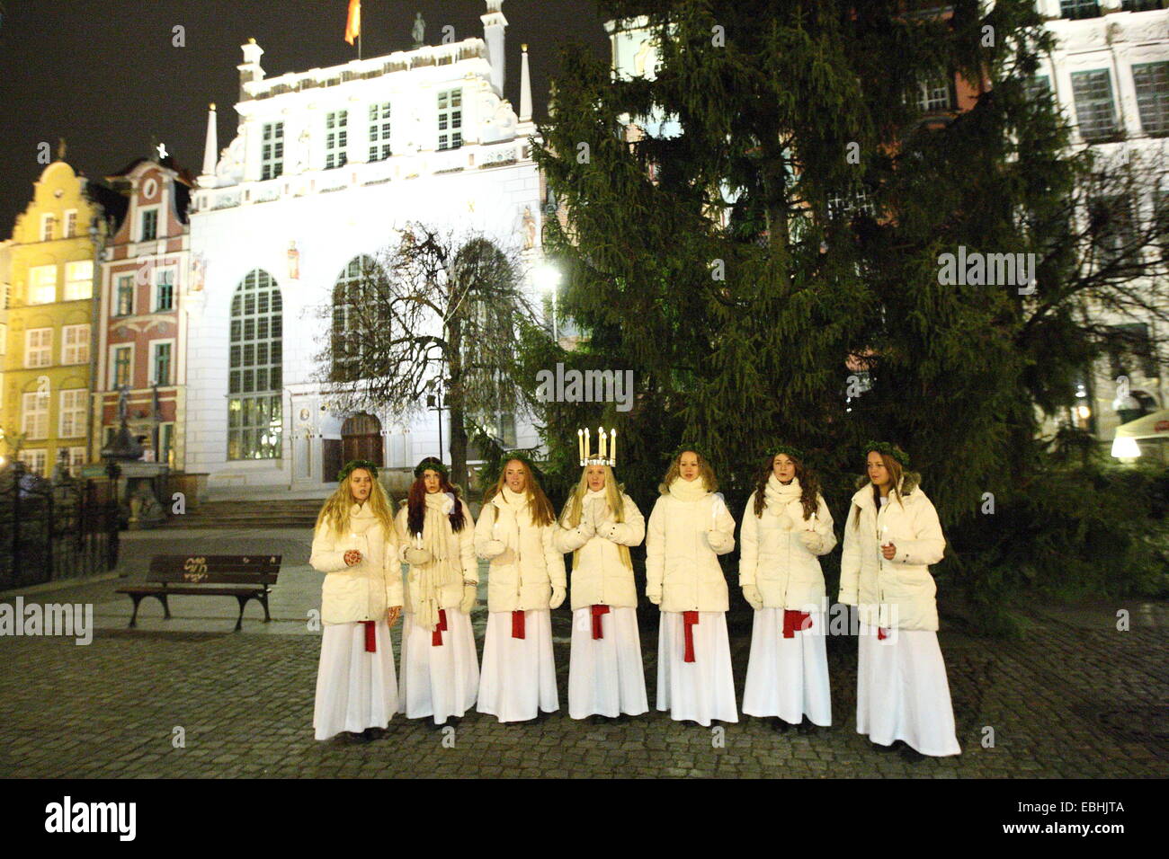 Gdansk, Poland 1st, Dec. 2014 Young girls from Kalmar, Sweden dressed in a white dress and a red sash (as the symbol of martyrdom) carries candles in proccesion along the Gdansk Old City centre. One of them (Stina Mattisson) wears a crown of candles on her head. Girls dressed as Lucy carry cookies in procession and sing a songs. It is said that to vividly celebrate St. Lucy's Day will help one live the long winter days with enough light. Credit:  Michal Fludra/Alamy Live News Stock Photo