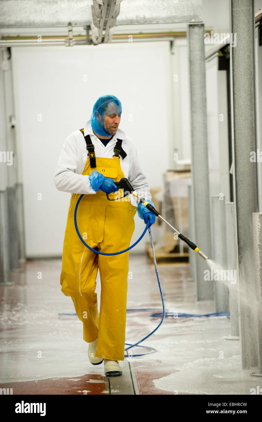 Man hosing down inside a meat factory Stock Photo