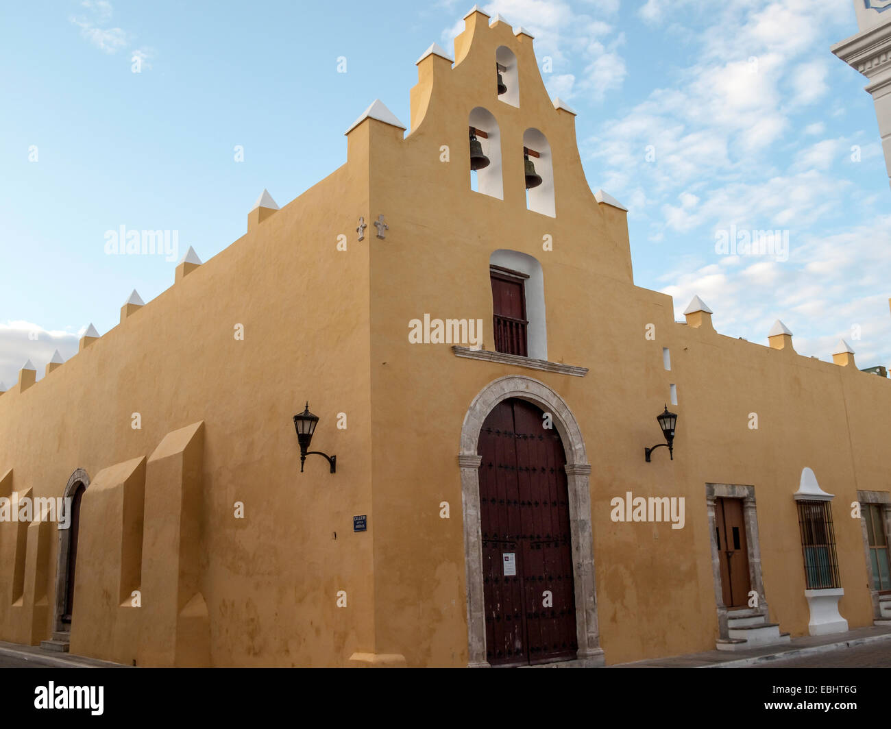 Corner view of 16th century Iglesia de San Francisco Church with ocher colored walls, red arched front door, three church bells  Campeche, MX. Stock Photo
