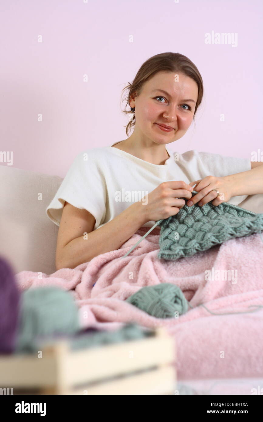 happy young woman knitting on sofa Stock Photo - Alamy