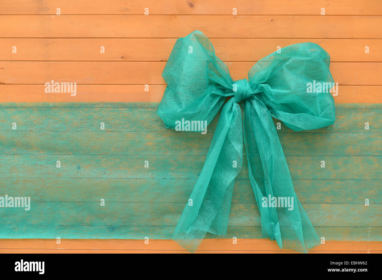 Big green ribbon on wood. Used as background, space for text. Stock Photo