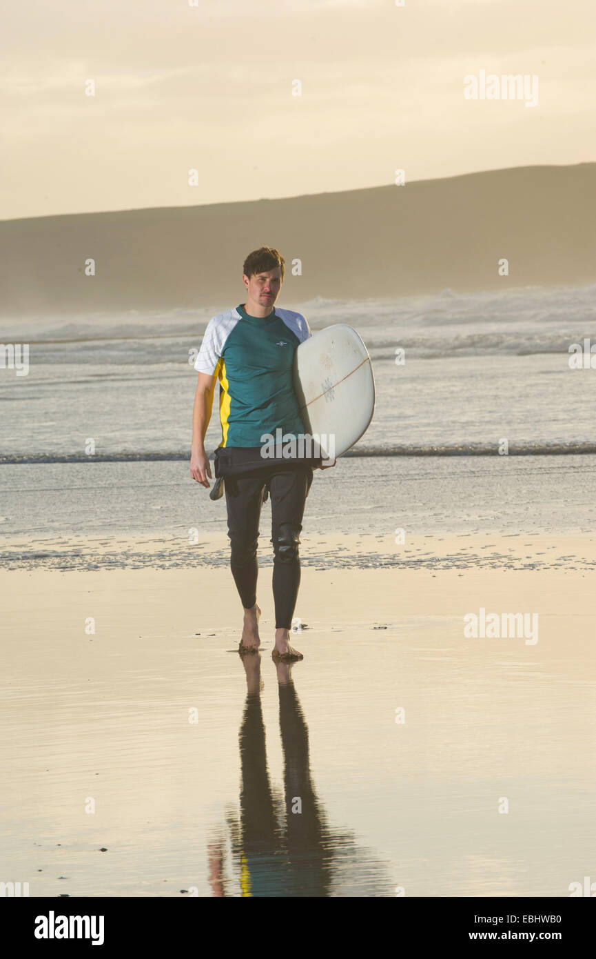 Surfer looking out to sea holding surfboard Stock Photo