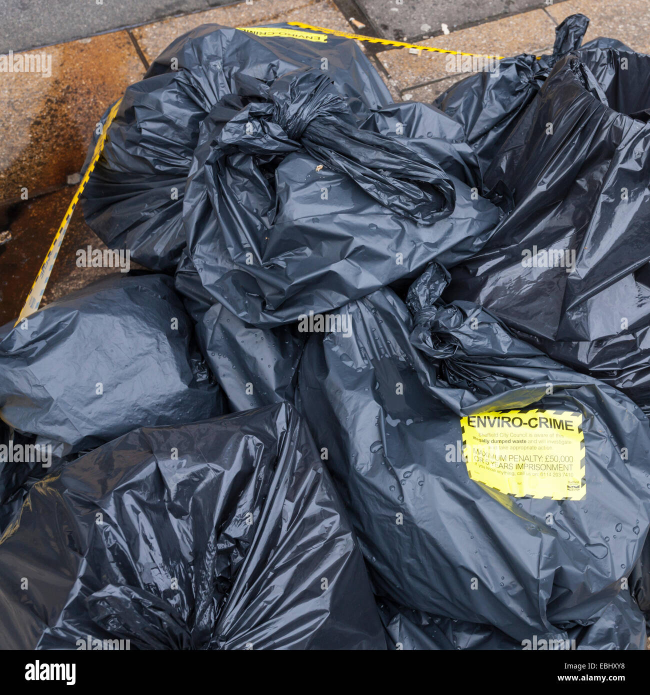 Environmental crime scene. Notice attached to bags of illegally dumped rubbish on a street. Sheffield city centre, England, UK Stock Photo