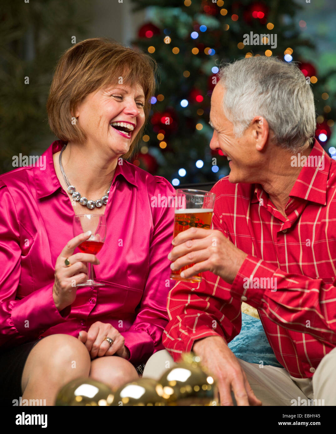 Man and woman having a Christmas drink with Xmas tree in background Stock Photo