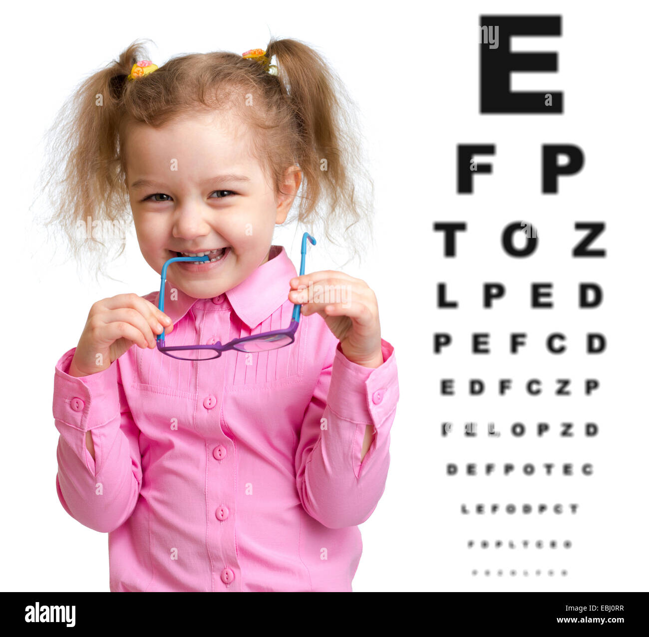 Smiling girl took off glasses with blurry eye chart behind her Stock Photo