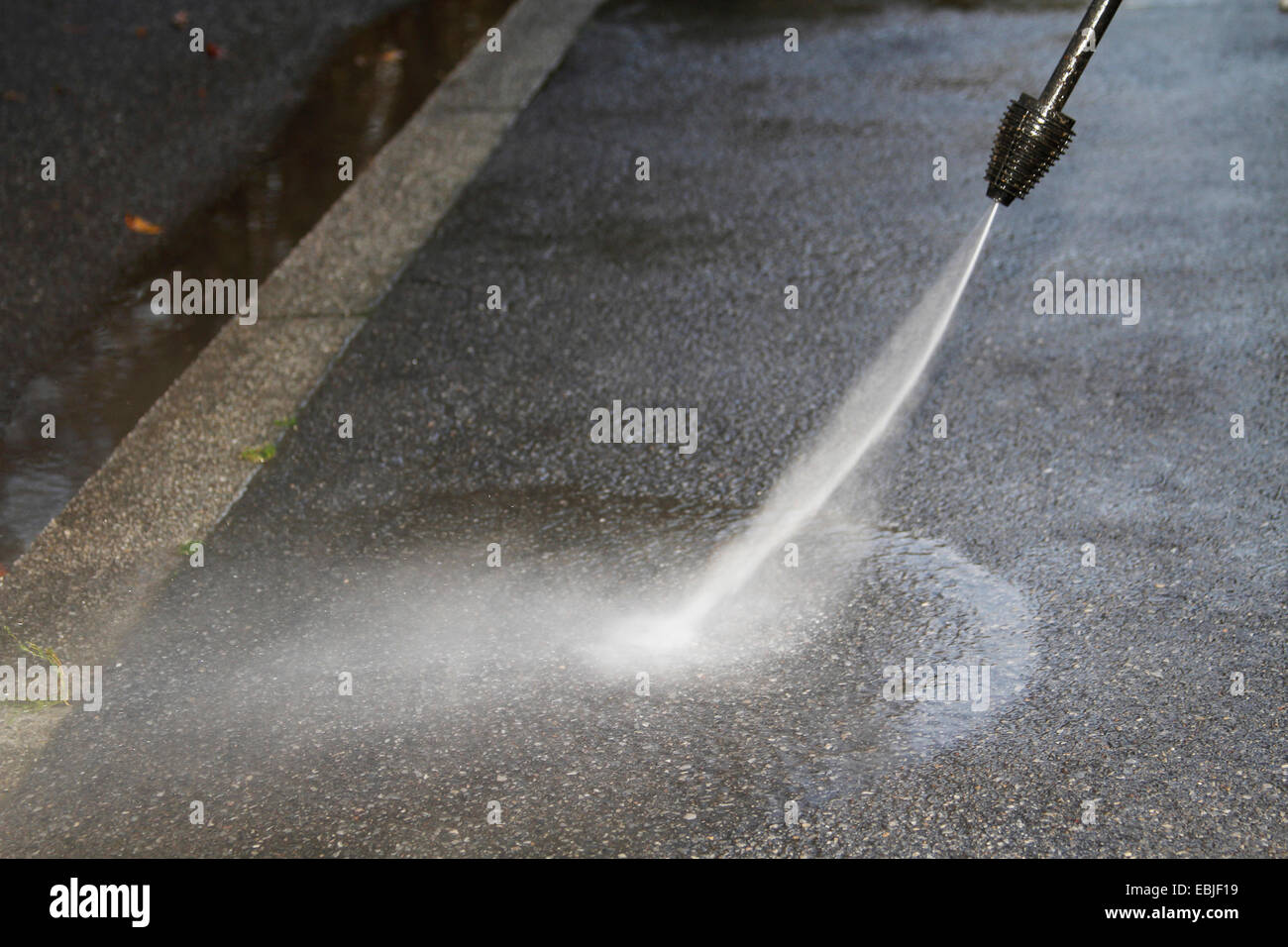 asphalt road being cleaned with a high-pressure water blaster, Germany, NRW, Ruhr Area, Essen Stock Photo