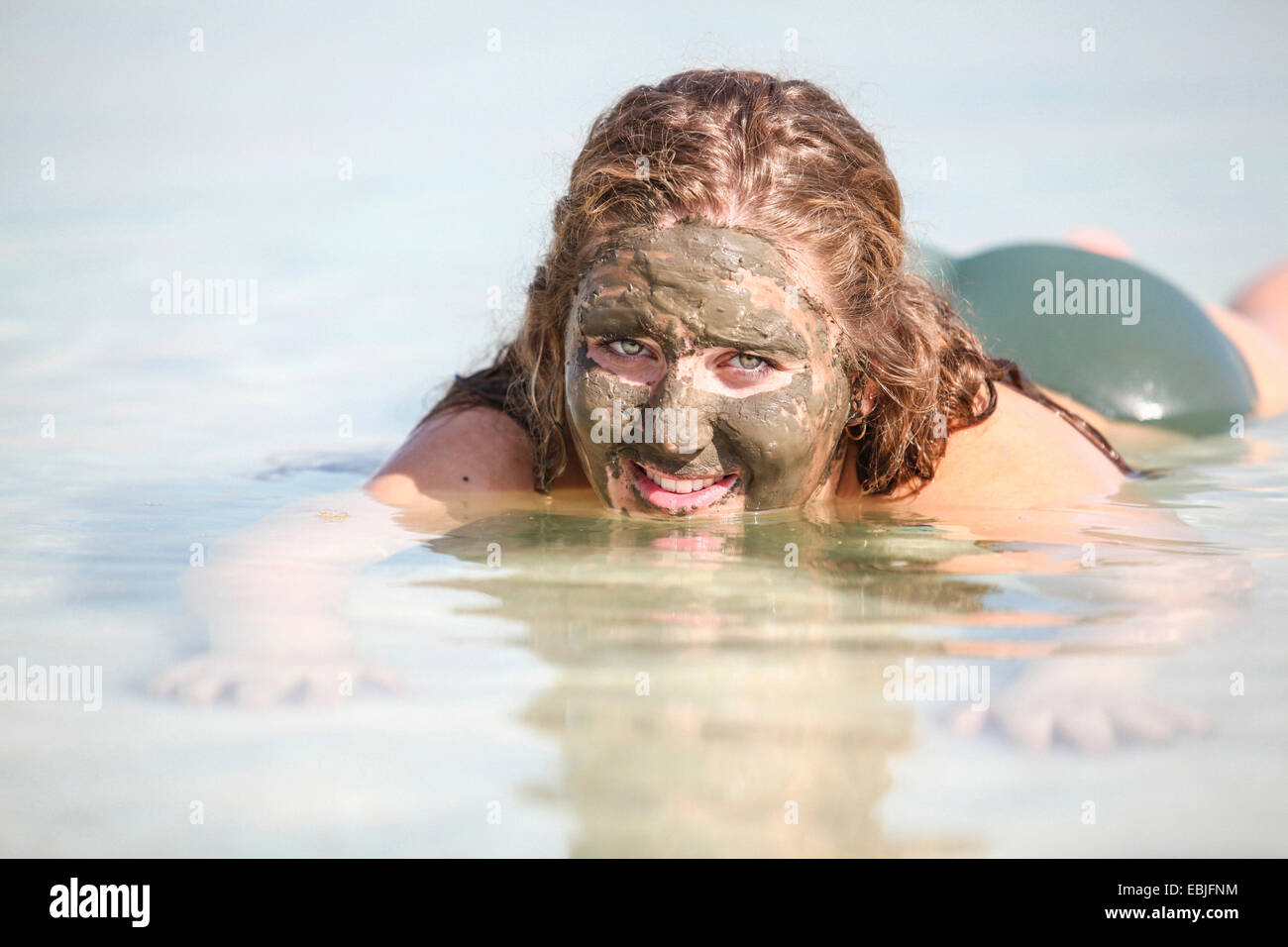 Mud covered female tourist floats in the Dead Sea, Israel Stock Photo