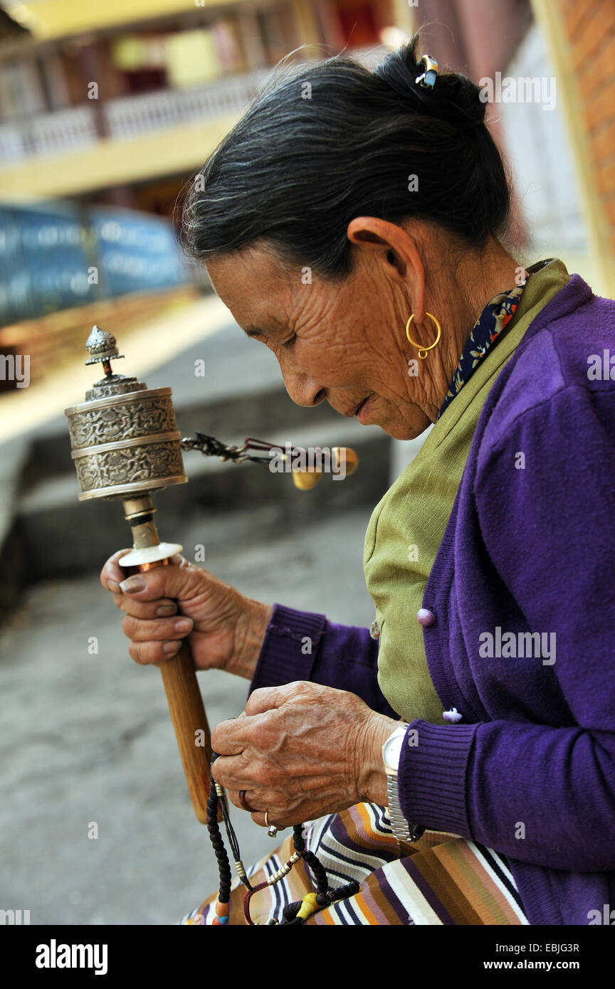 old buddhist woman in a monastry  is sunk in a prayer with a prayer wheel in the hand, Nepal, Pokhara Stock Photo