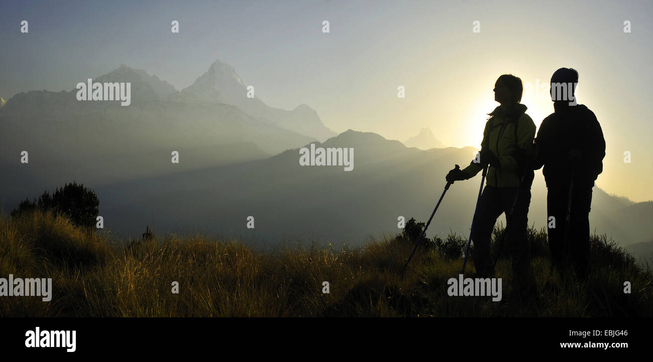 silhouettes of two mountain hikers in front of the rising sun on Poon Hill at the Annapurna Massif, Nepal Stock Photo