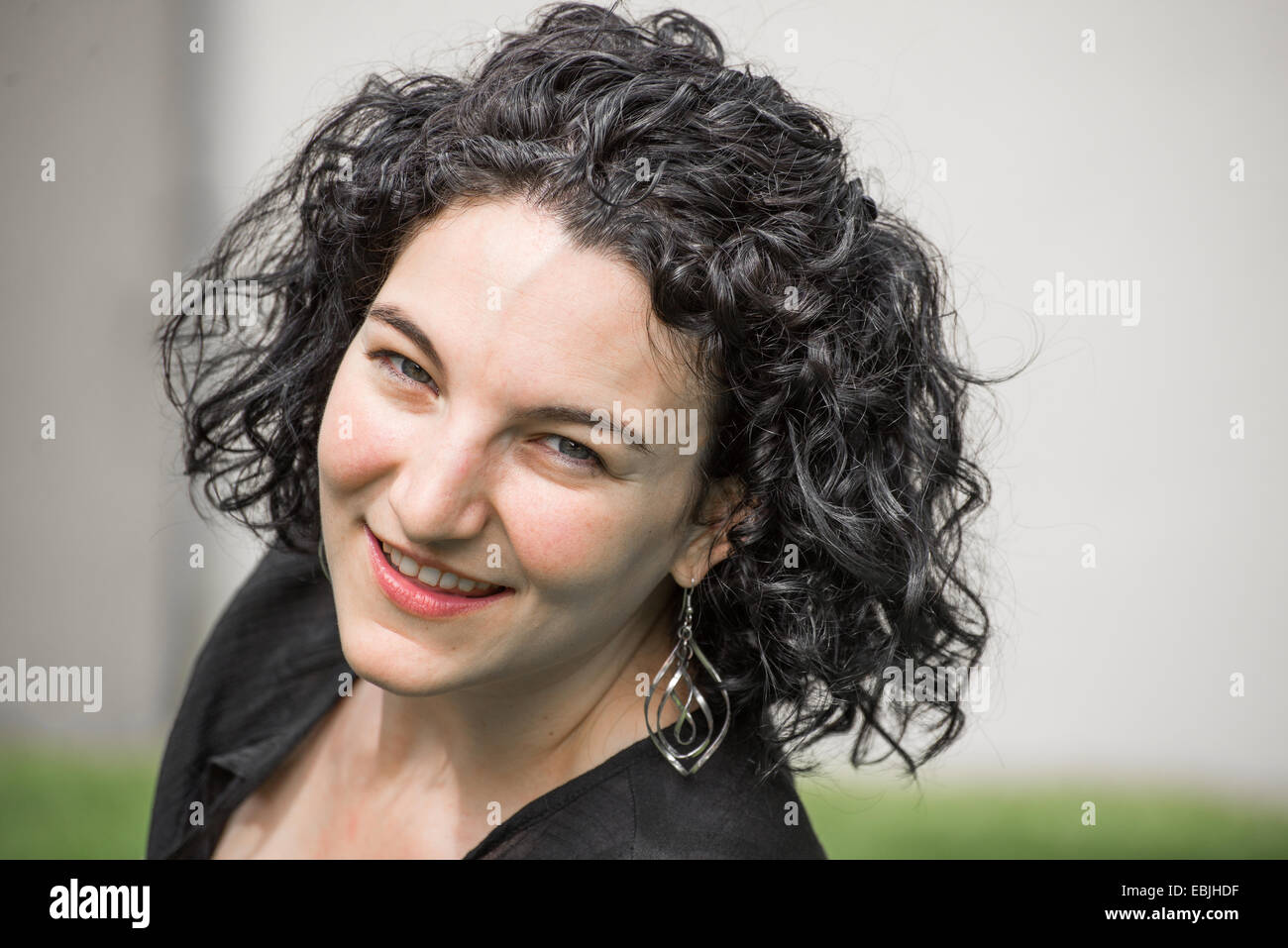 A portrait of a young woman in her early twenties. She has black hair and she is wearing a black top. Stock Photo