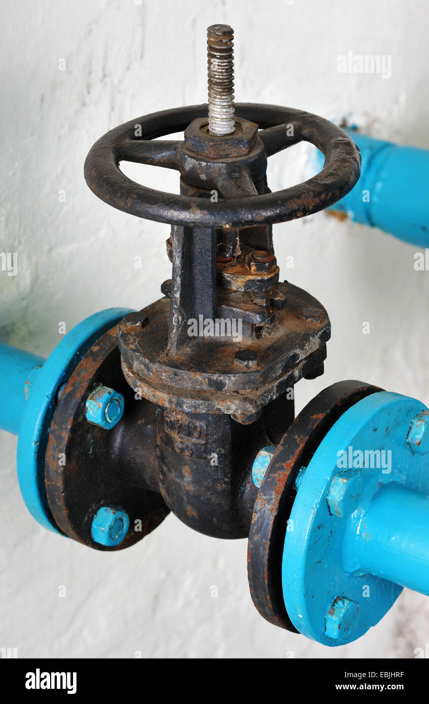 Unpainted water valve made of cast iron on the background of whitewashed walls Stock Photo