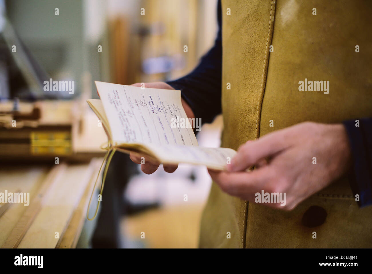 Close up of mid adult craftsman holding notebook in organ workshop Stock Photo