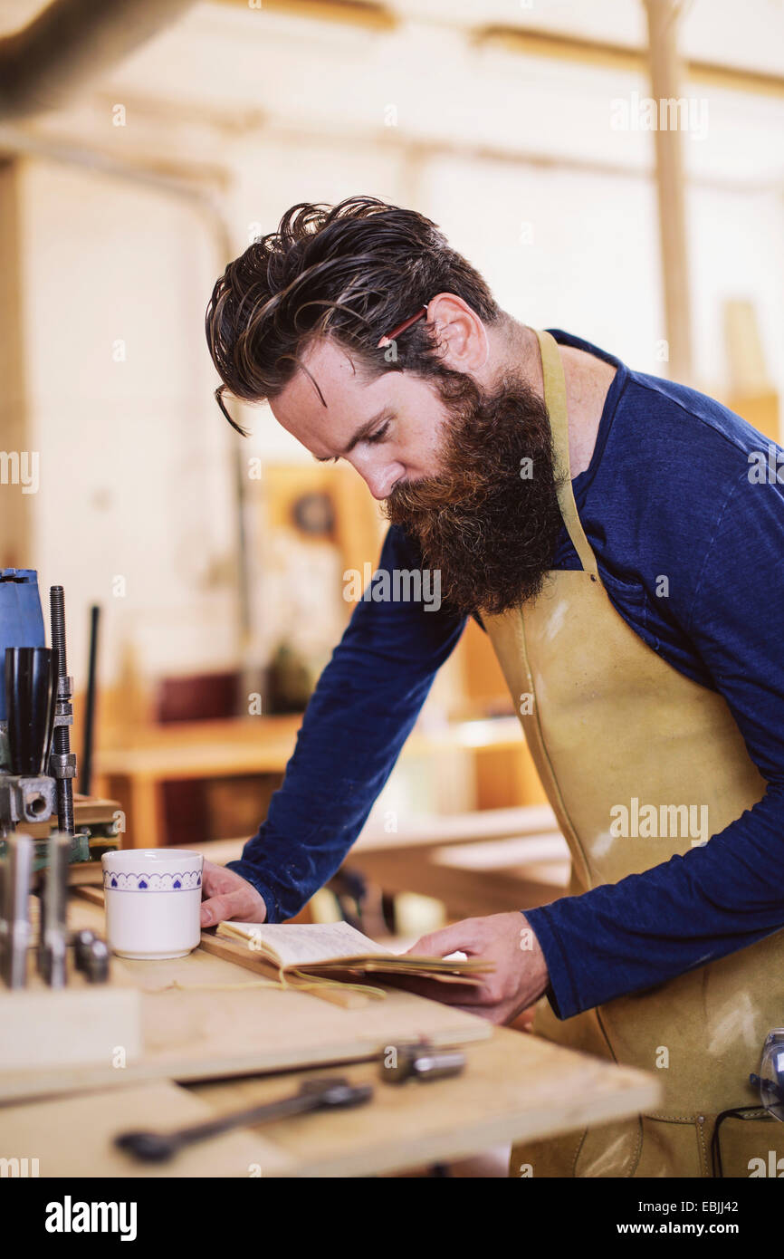 Mid adult craftsman checking notebook in organ workshop Stock Photo