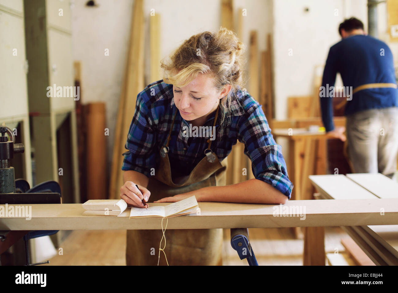 Young craftswoman making notes in pipe organ workshop Stock Photo