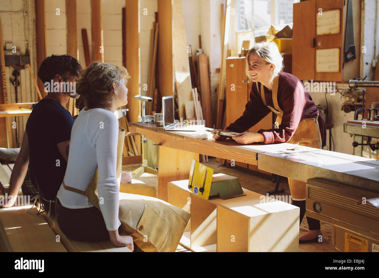 Three craft workers having an informal meeting in pipe organ workshop Stock Photo