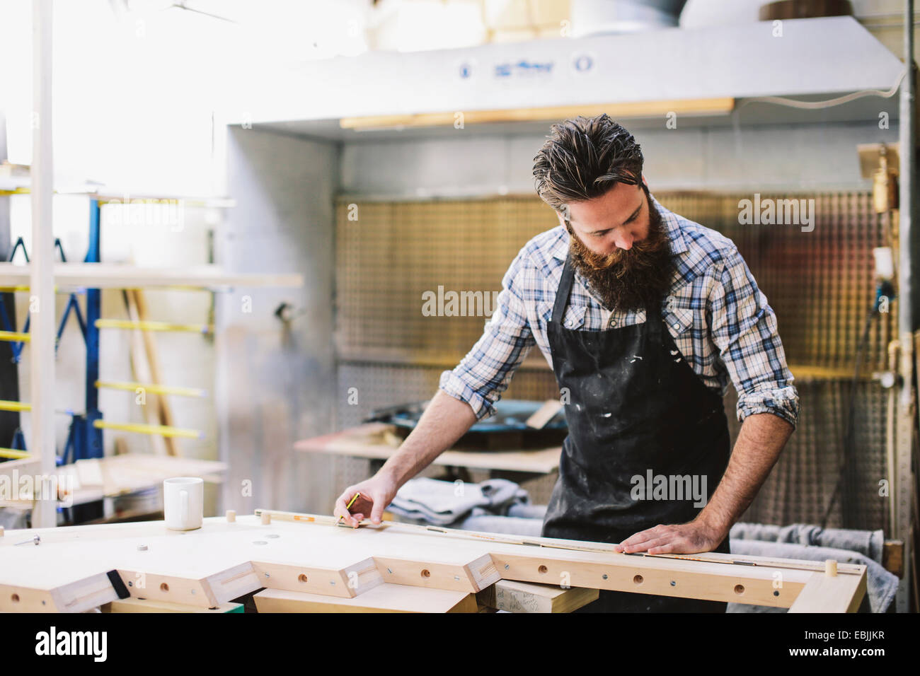 Cropped shot of mid adult craftsman measuring wood in organ workshop Stock Photo