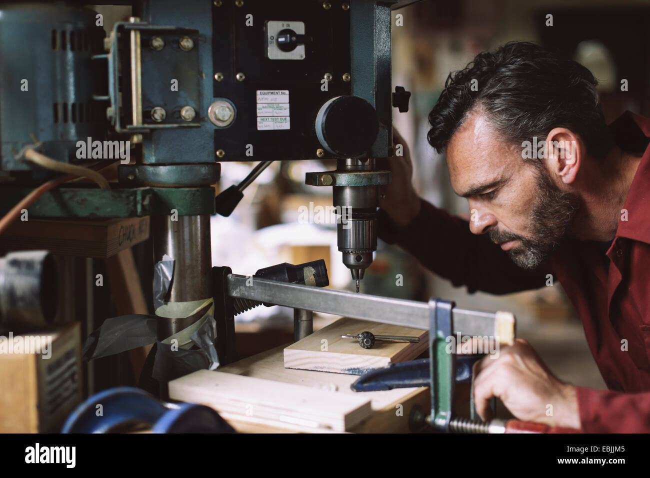 Mature craftsman drilling component in pipe organ workshop Stock Photo