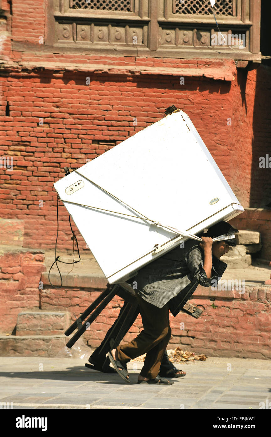 man carrying a freezer on the back through the streets with the help of a headband, Nepal, Kathmandu Stock Photo