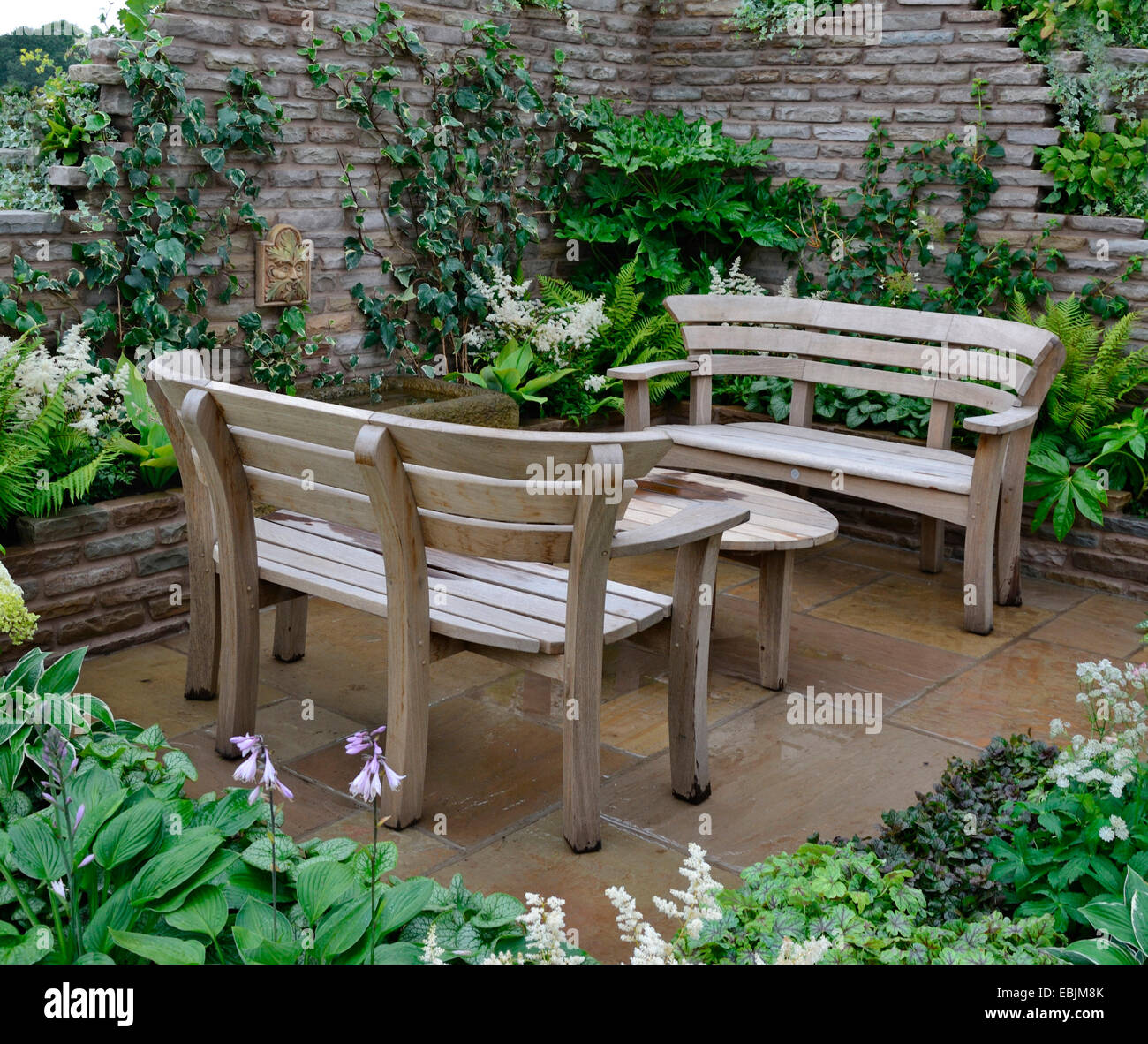 Close up of a wooden garden seats in a walled garden patio Stock Photo