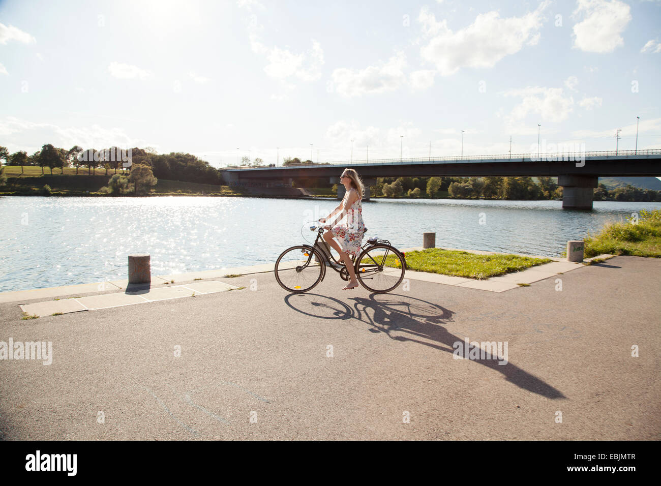 Young woman cycling at riverside, Danube Island, Vienna, Austria Stock Photo