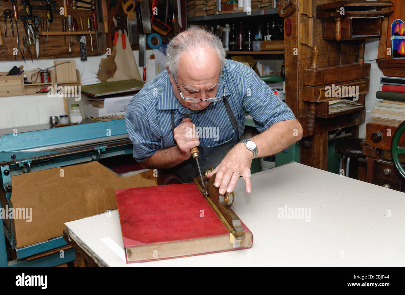 Senior man restoring book in traditional bookbinding workshop Stock Photo