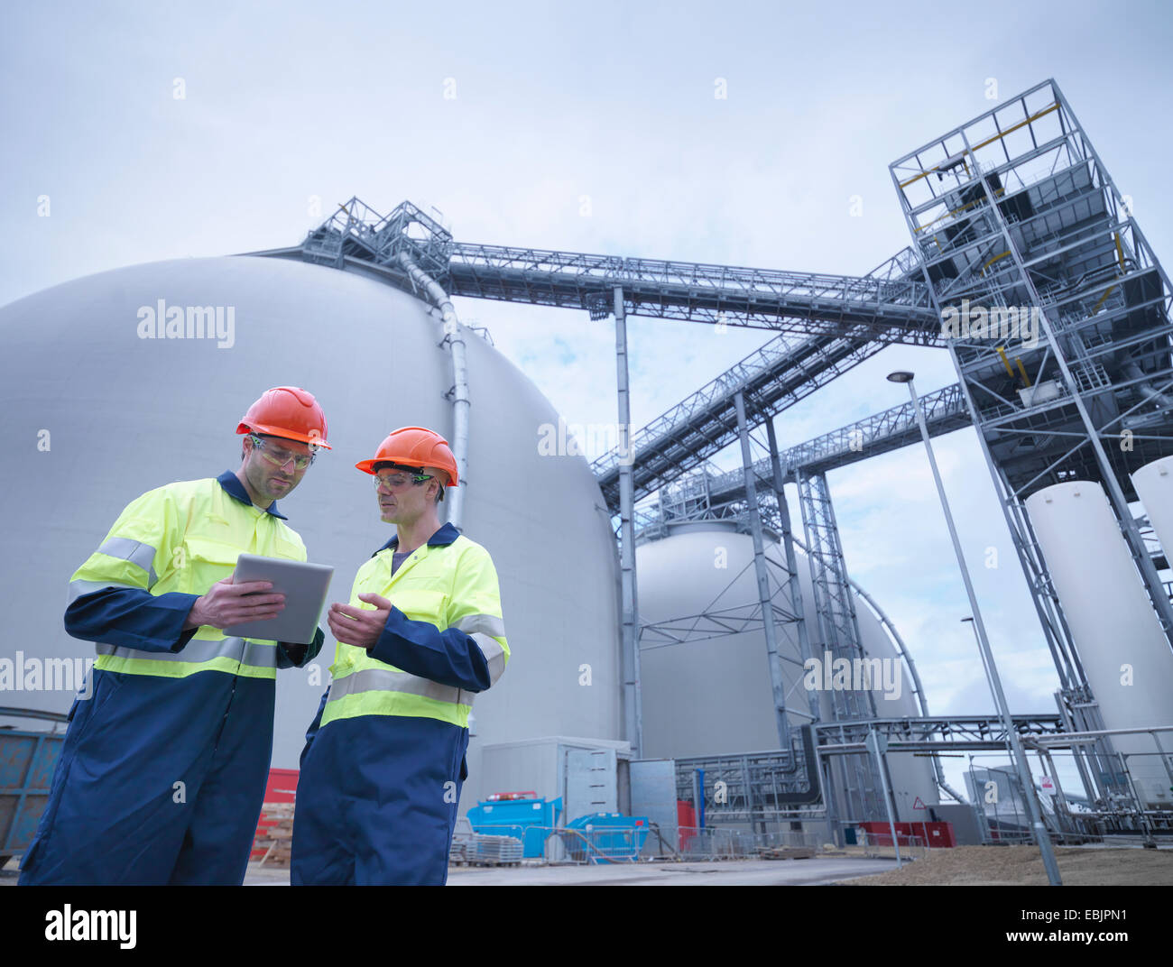 Workers using digital tablet at biomass facility Stock Photo