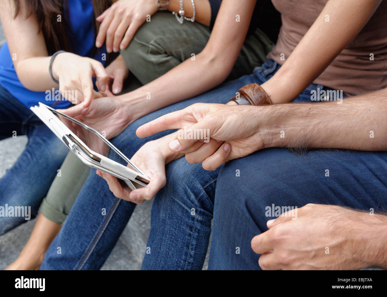 Group of friends looking at digital tablet, focus on tablet and hands Stock Photo