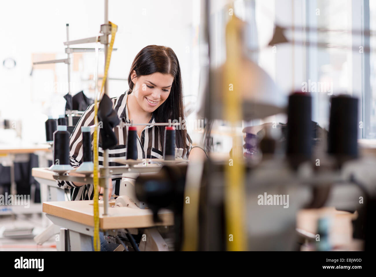 Young female seamstress using sewing machine in workshop Stock Photo