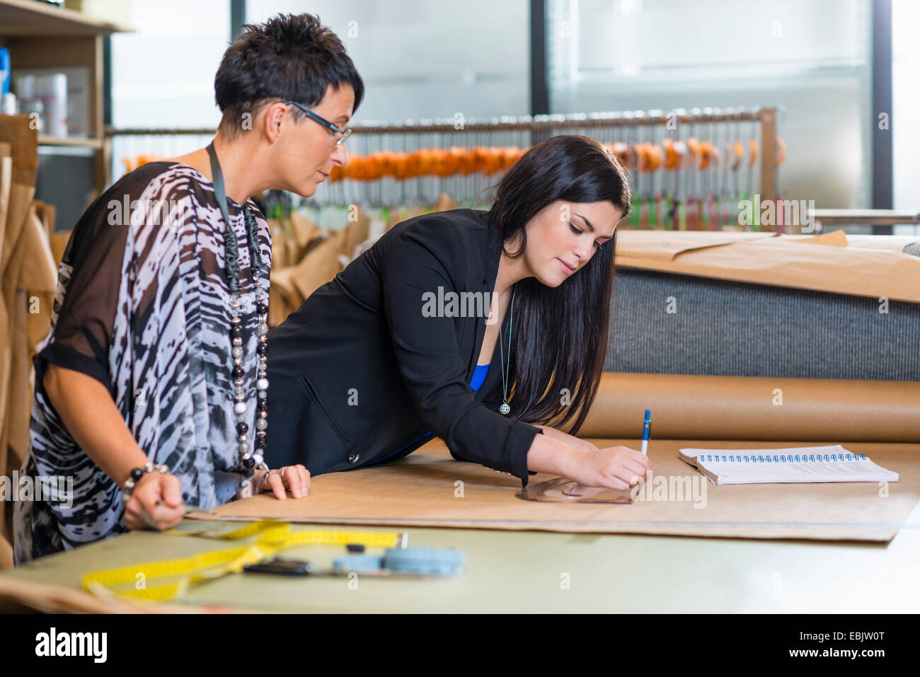 Two seamstresses drawing dressmakers pattern in workshop Stock Photo