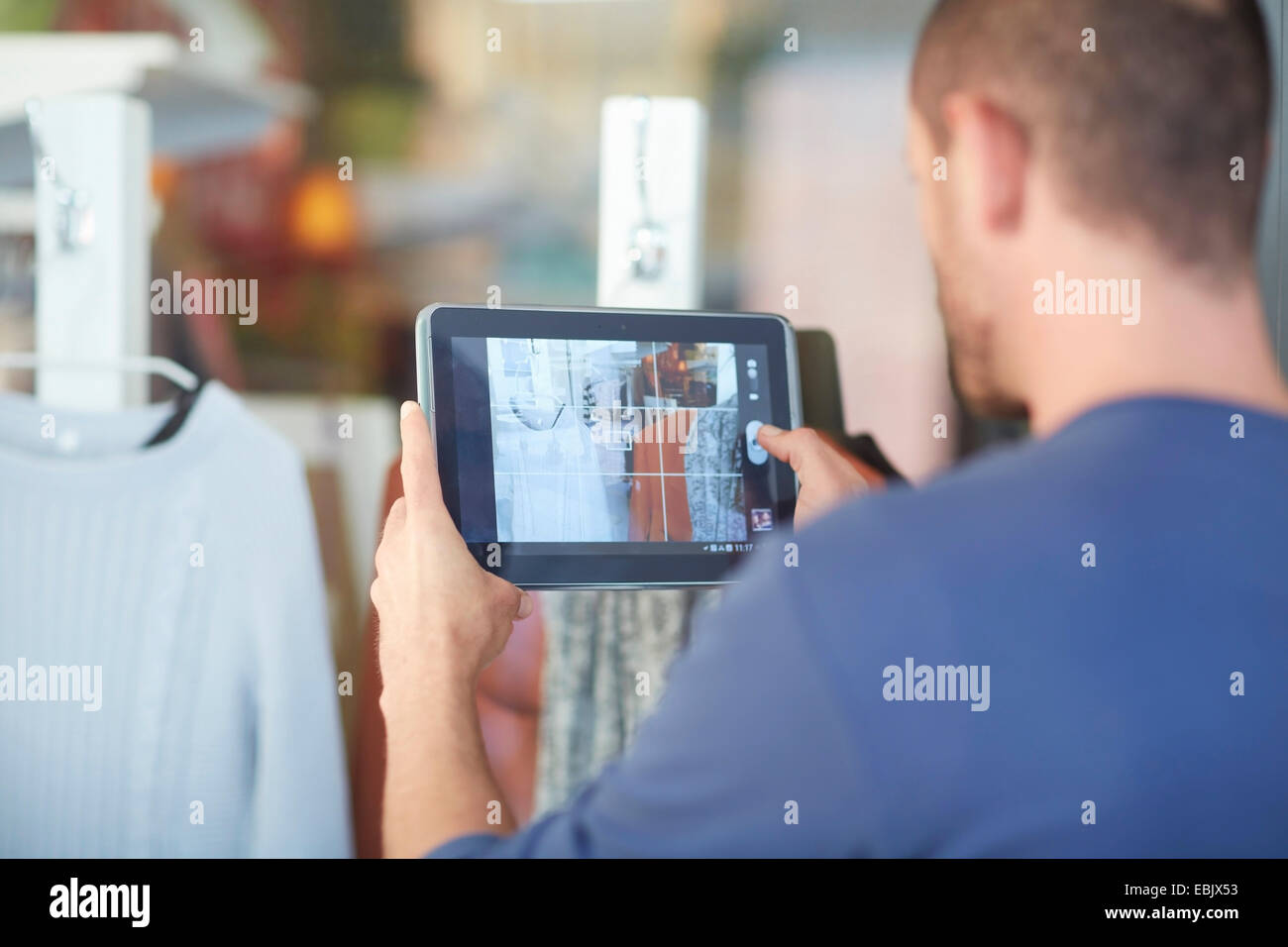 Mid adult man holding digital tablet, taking photograph of shop window Stock Photo