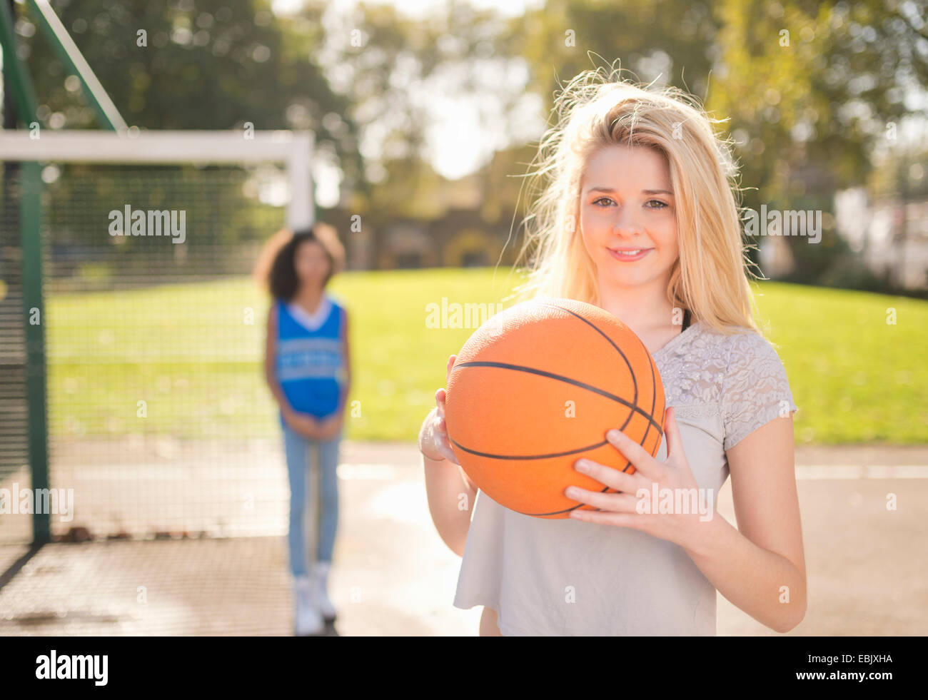 Portrait of young woman holding up basketball Stock Photo