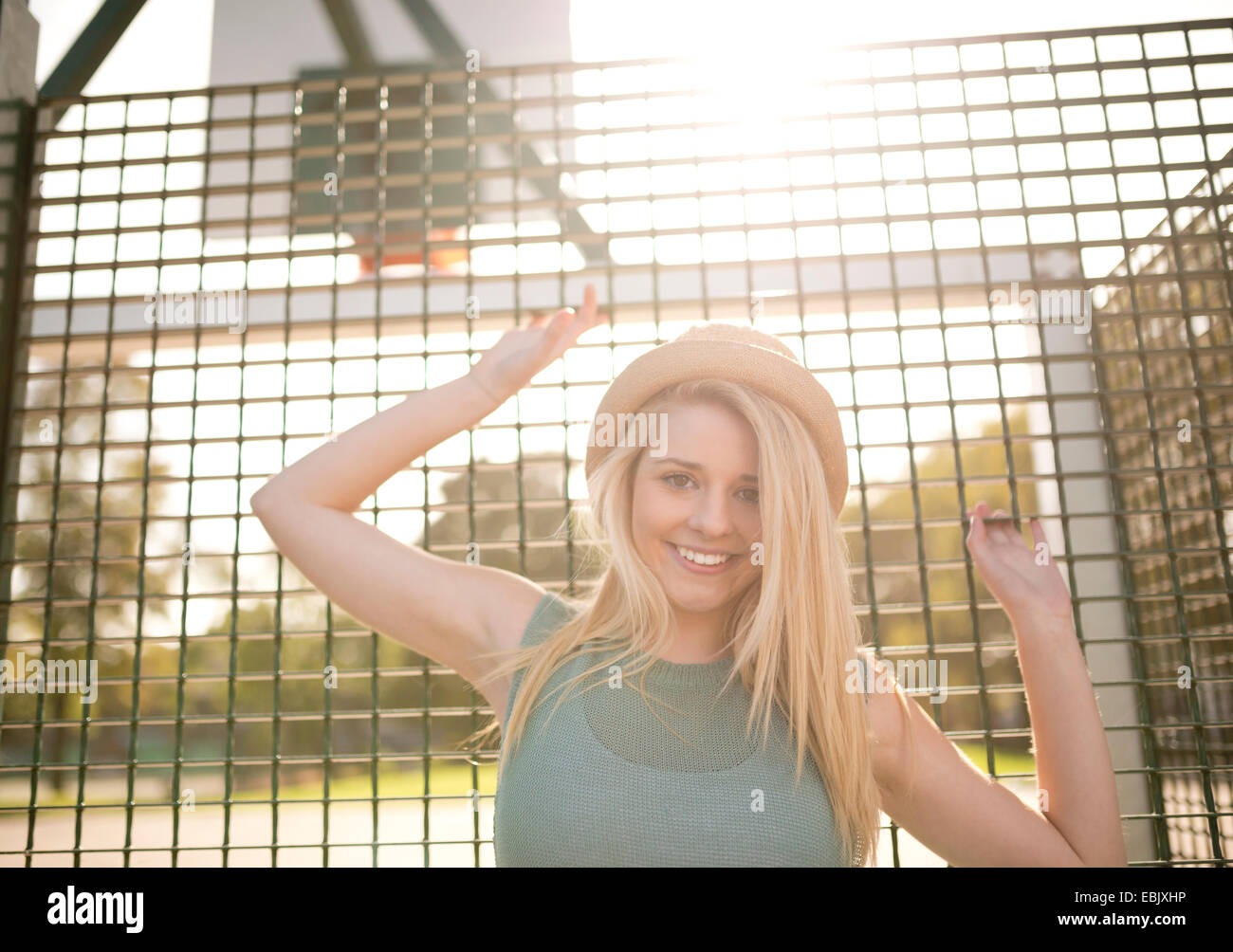 Portrait of young female basketball player holding onto wire fence Stock Photo