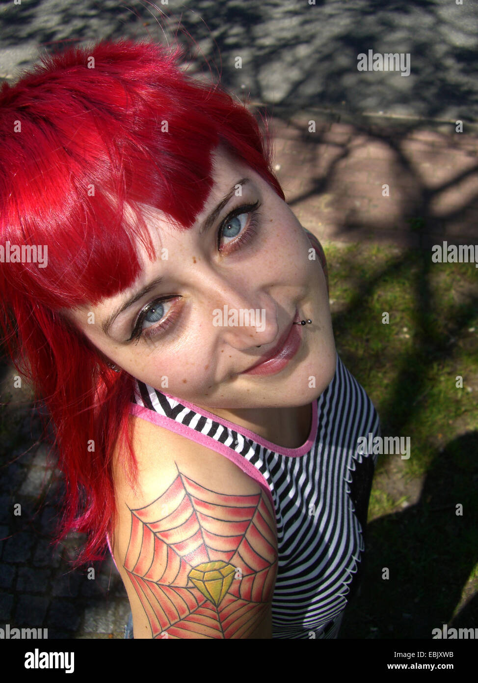 young tattooed redheaded woman looking up to the camera Stock Photo