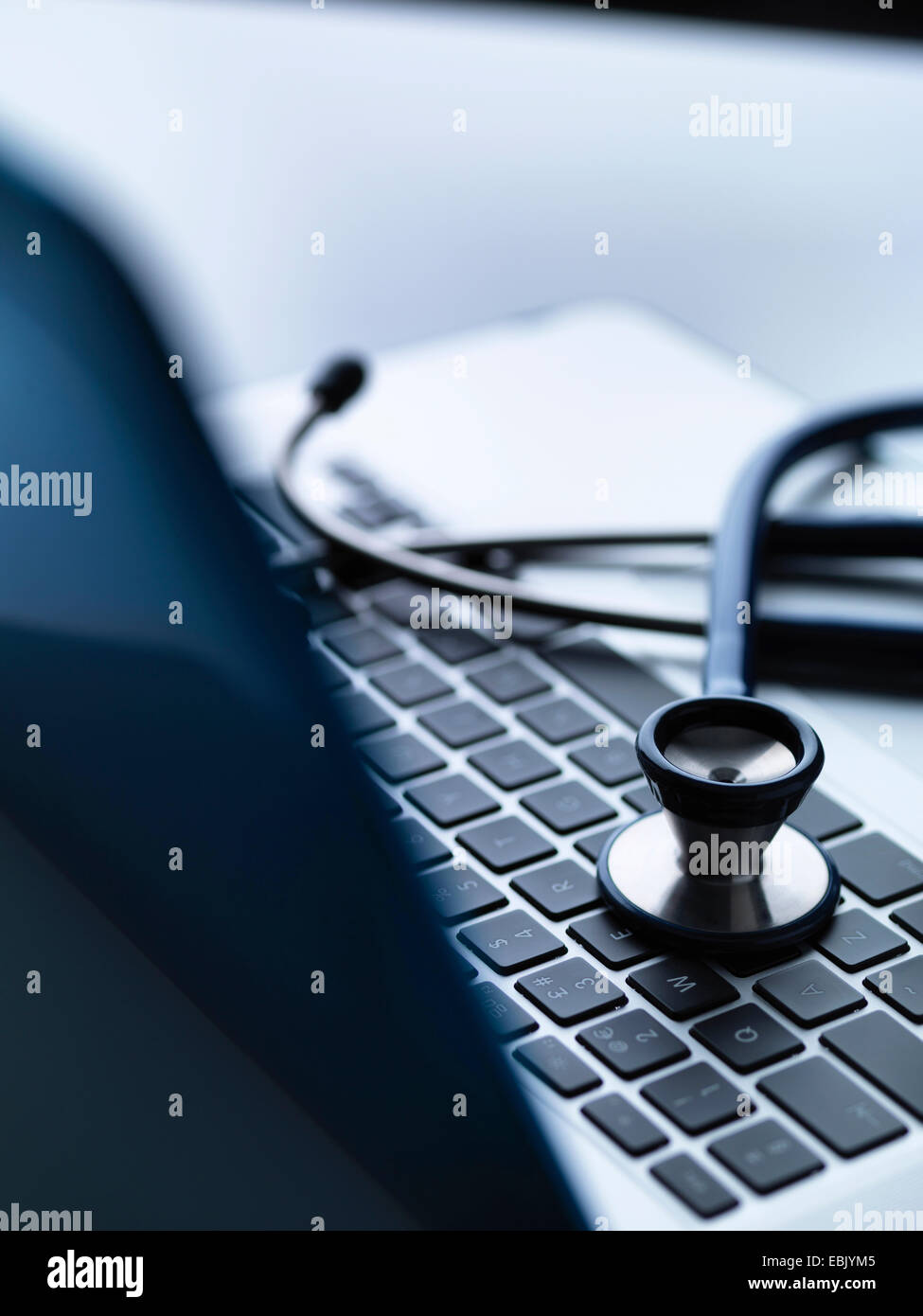 Stethoscope on top of laptop computer keyboard on doctors desk Stock Photo