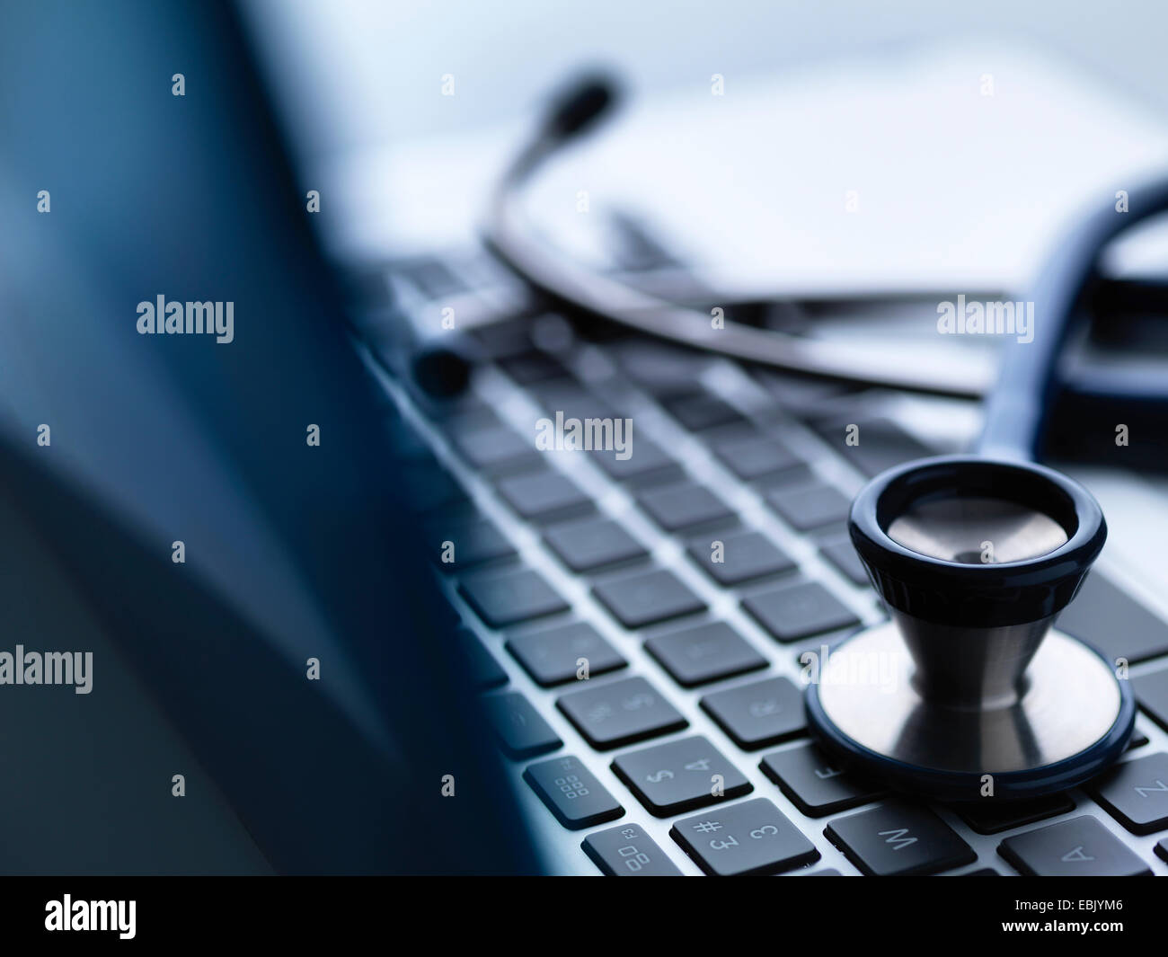 Close up of stethoscope on top of laptop computer keyboard on doctors desk Stock Photo