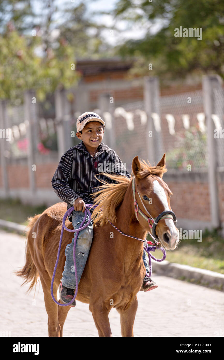 A young Mexican cowboy herds livestock down a village street by Mexican cowboys November 5, 2014 in Yaguar, Mexico. Stock Photo