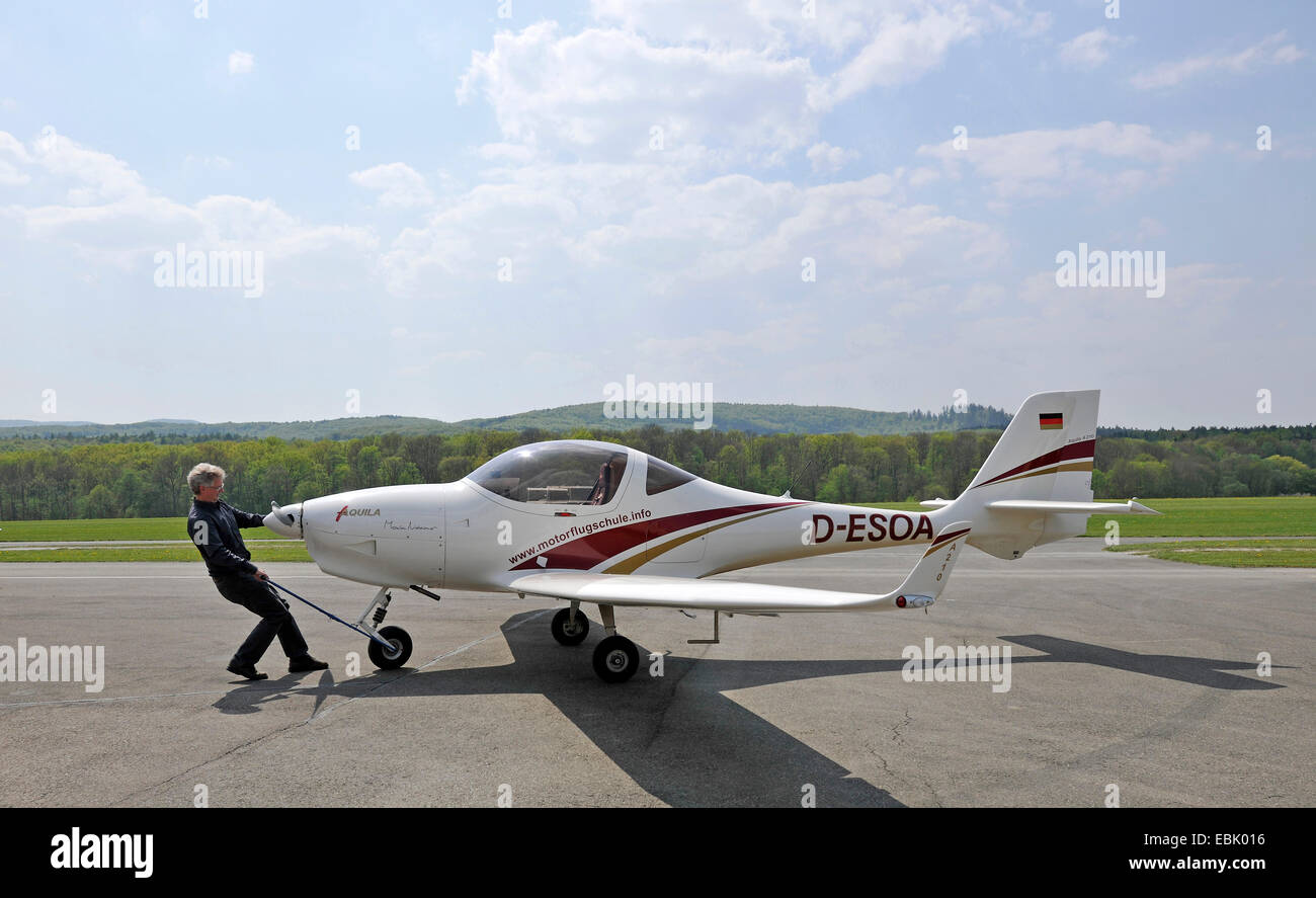 pilot at the airport Hahnweide pulling the small aircraft D-ESOA Aquila A210 AT01 with a drawbar, Germany, Baden-Wuerttemberg, Kirchheim Unter Teck Stock Photo