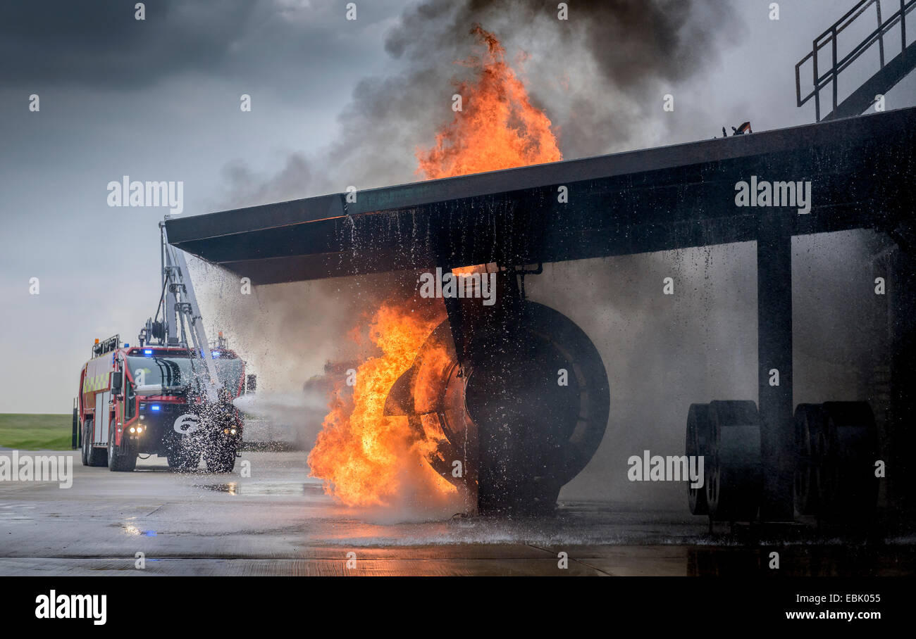 Fire engine spraying water on simulated fire at airport training facility Stock Photo