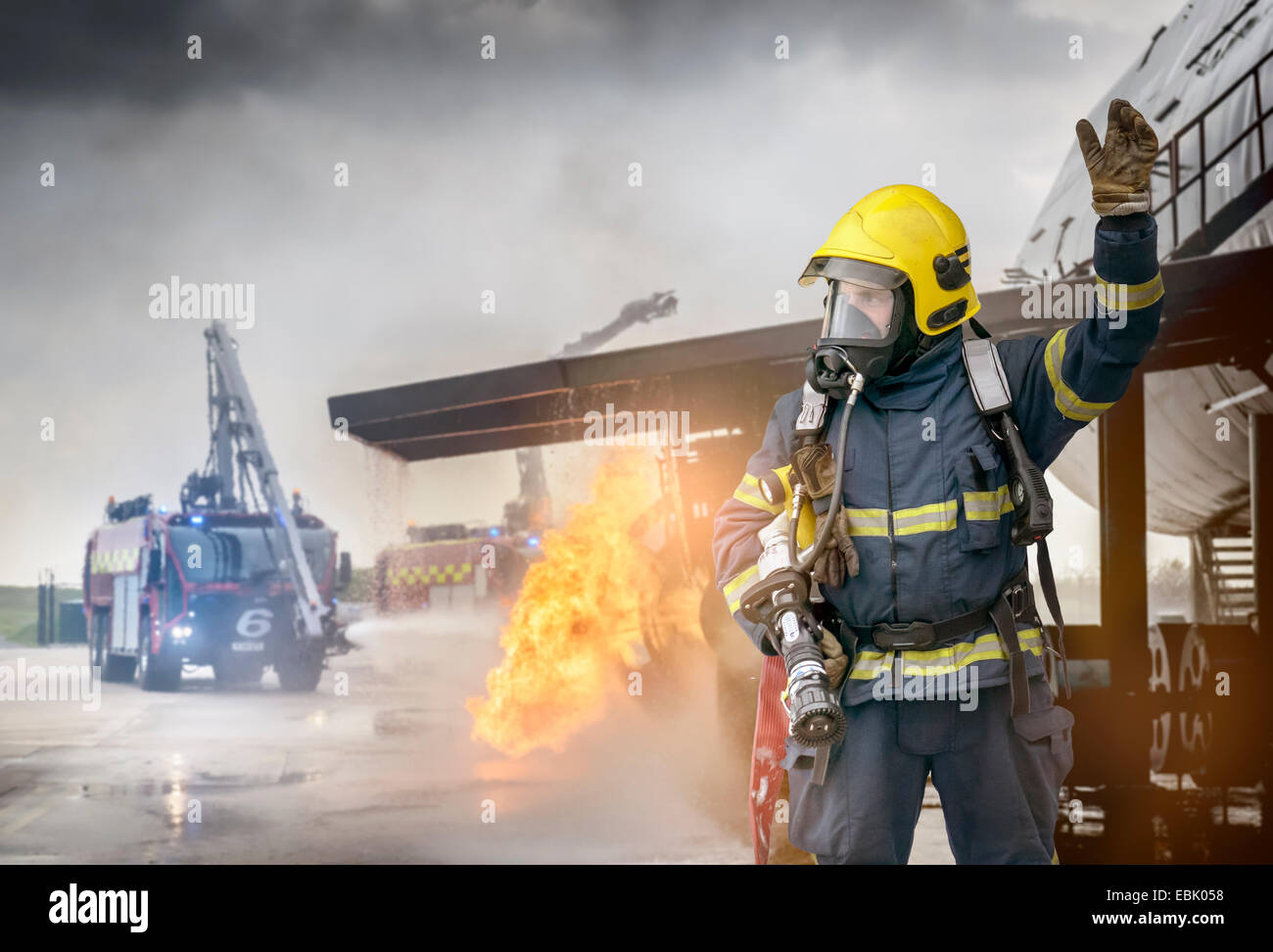 Portrait of fireman in front of simulated fire at airport training facility Stock Photo