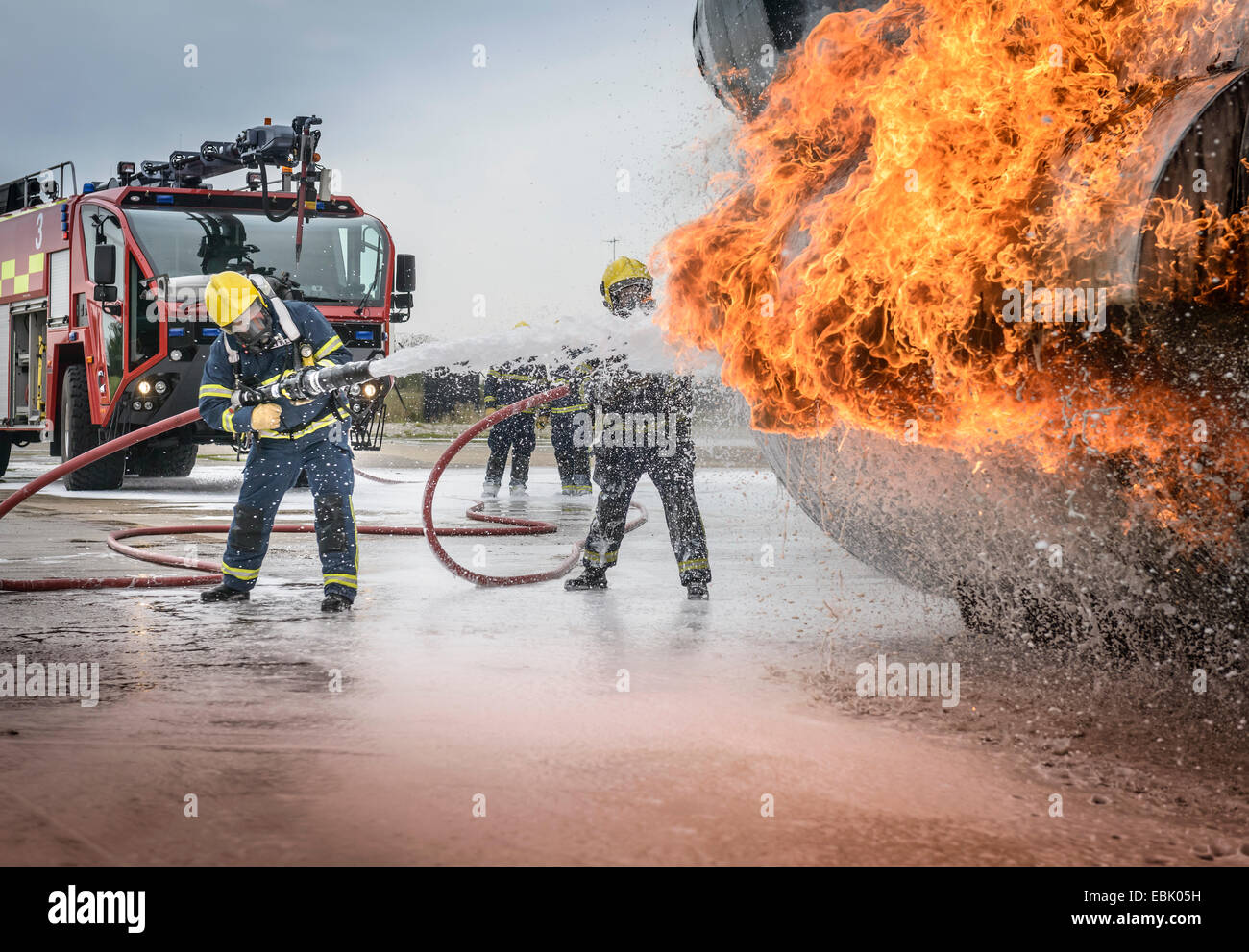 Firemen spraying water on simulated aircraft fire at training facility Stock Photo