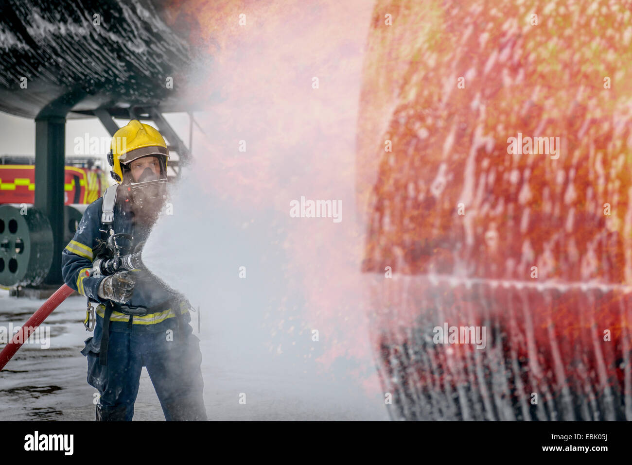 Fireman spraying water on simulated aircraft fire at training facility Stock Photo