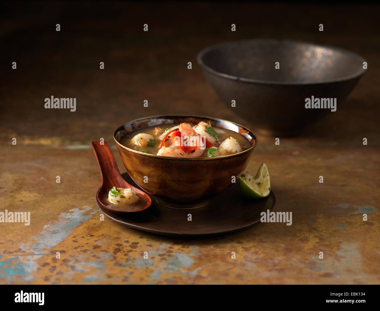 Bowl of tom yum soup with prawns, chilli and squeezed lime Stock Photo