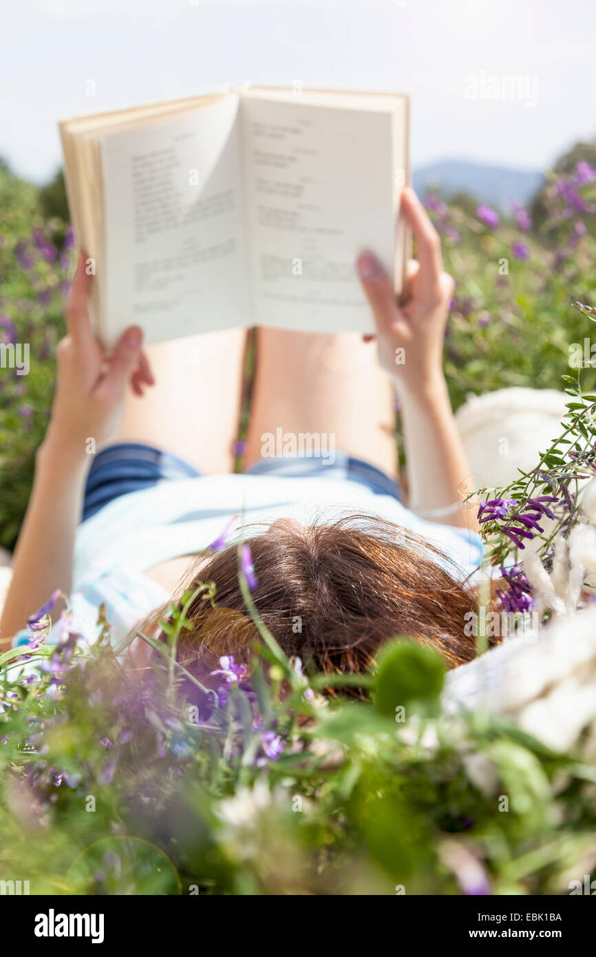 Young woman lying in field reading book Stock Photo